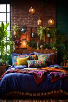 a bed covered in lots of pillows and blankets next to a wall with potted plants