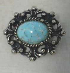 "A beautiful Art Deco Blue Peking Czech Glass Pin Brooch. The fabulous vintage brooch features a large central Turquoise Blue Peking glass surrounded by a decorative silver tone metal mount. The Peking Czech Glass cabochon looks just like Blue Turquoise stone. Peking Glass is layered glass, one colour layered over another with the top layer carved away to reveal the lower layer colour. In the 1920s and 30s, the Czechs began to make Chinese-style jewelry and made layered glass that was called \"P Vintage Blue Brooches For Jewelry Making, Vintage Brooch With Antique Finish, Vintage Oval Brooch With Cabochon, Vintage Oval Cabochon Brooch, Blue Oval Brooch, Vintage Oval Brooches For Collectors, Handmade Vintage Turquoise Brooches, Deco Blue, One Colour