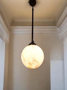 a light fixture hanging from the ceiling in a room with white walls and trimmings