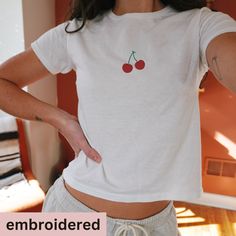 *Please note, holiday shipping times may be longer than normal. Please allow at least 7 days for shipping*  embroidered crop top with Cherries. This is a slim fit, for a looser fit, we recommend sizing up.  Product details  * 52% combed ring-spun cotton, 48% polyester * 40 singles * Slim fit RETURNS OR EXCHANGES All of our shirts are custom printed to order, made just for you, so we do not accept returns or exchanges due to color or fit/size. If there are any issues with the shirt, please messag Cute White Cotton Cropped T-shirt, Basic Cotton Cropped T-shirt For Summer, Fitted Short Sleeve T-shirt With Cherry Print, Trendy Embroidered Short Sleeve Tops, Fitted Short Sleeve Top With Cherry Print, Fitted Short Sleeve Cherry Print T-shirt, Cute Cropped Cotton T-shirt, Fitted Cherry Print T-shirt With Short Sleeves, Fitted Cherry Print Short Sleeve T-shirt