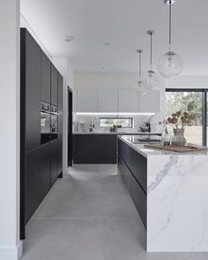 a large kitchen with marble counter tops and black cabinets, along with an island in the middle