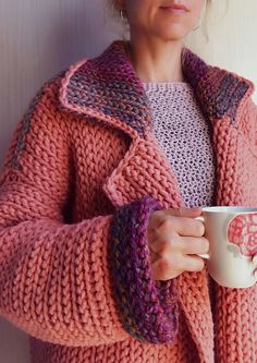 a woman is holding a coffee cup in her hand and wearing a knitted sweater