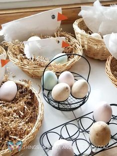 several baskets filled with eggs sitting on top of a white table next to paper birds