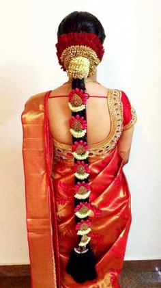 the back of a woman's head wearing an orange and red saree with gold accents