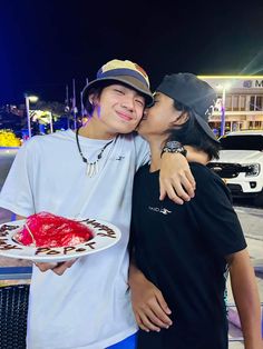 two people standing next to each other holding a plate with a cake on it in front of them