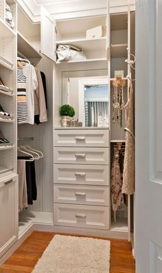 a walk in closet with lots of white drawers