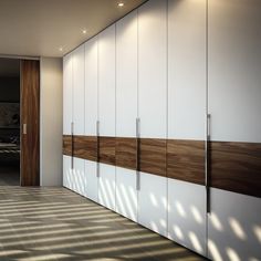 an empty room with white cupboards and wood paneling on the wall next to a door