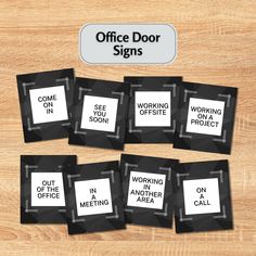 six black and white office door signs sitting on top of a wooden table