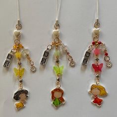 three charms are hanging from the side of a white surface, each with different designs on them