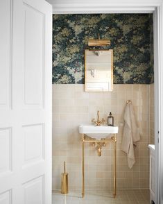 a white sink sitting under a mirror next to a wall mounted faucet in a bathroom