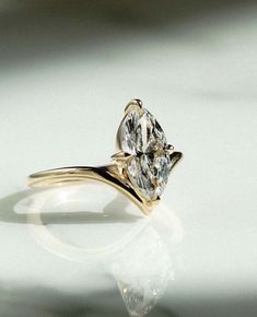 a yellow gold ring with a pear shaped diamond in the center on a white surface