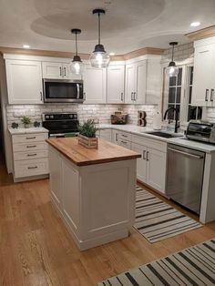 a kitchen with white cabinets and wooden counter tops, an island in between the stove and sink