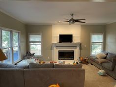 a living room filled with furniture and a flat screen tv mounted on the wall above a fire place