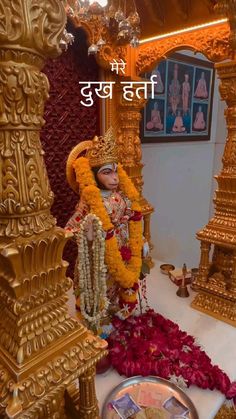 the statue is surrounded by flowers and other decorations in front of a gold pillar with an inscription on it