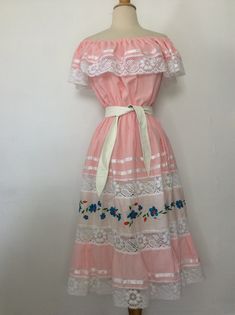 "Vintage Dress 1970's Vintage Oaxacan Mexican Wedding Dress Pink Cotton or Cotton Blend. No tags Elastic Top, so can be worn Off or On Shoulder 6\" Ruffle with White Lace and Ribbon Trim Elastic Waist The Skirt has 2 Sheer Lace Inserts with an Embroidered Panel in between I have it shown with and without a belt. Belt Not Included. No size tag, so Please go by measurements taken laid flat seam to seam 20-23\" armpit to armpit 10-21\" waist 26\" hips 35\" long from armpit Excellent Vintage Conditi 1970s Mexican Fashion, Mexican Pink Dress, Mexican Dress Aesthetic, Pink Mexican Outfit, Summer Bohemian Vintage Dress In White, Bohemian Vintage White Dress For Summer, Summer Bohemian Vintage White Dress, Bohemian Vintage White Summer Dress, Traditional Mexican Dress For Women