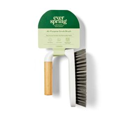 a green and white plastic brush sitting on top of a white wall next to a wooden handle