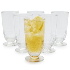 four clear glasses with lemon wedges in them