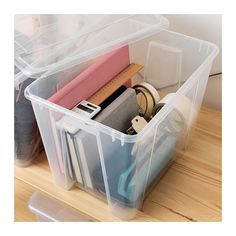 a plastic container filled with files and other office supplies on top of a wooden table