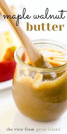 a jar filled with homemade walnut butter on top of a white table next to an apple