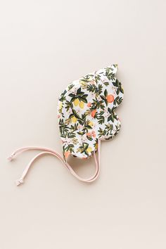 a pair of flowery hair clips on a white surface with pink cord and an orange floral print