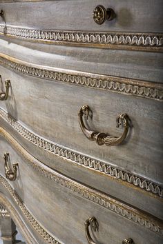 an antique dresser with gold handles and ornate carvings on the top, is shown in this image