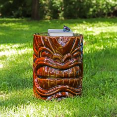 a wooden tiki statue sitting on top of a lush green field