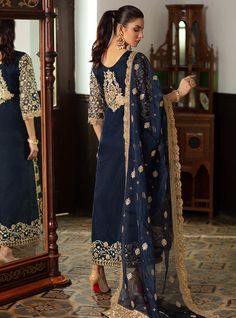 Embroidered Pakistani Suit In Navy Blue Color is a bold ensemble with some magnificent gold embellishments crafted on it giving it a royal yet charming look. This Pakistani Party Dress can be stitched in two styles according to the demand of our lovely customers. Gown: This Embroidered Pakistani Suit comes with a beautiful gown in open style half-cut. The fabric of this gown is organza and is beautifully emblazoned with fine embroidery, tilla, and iridescent sequins. Heavily embellished neckline Elegant Salwar Kameez With Gold Embroidery For Festivals, Elegant Sets With Gold Embroidery For Diwali, Gold Anarkali Lawn Suit With Intricate Embroidery, Elegant Unstitched Suit With Gold Embroidery, Designer Gold Lawn Suit For Diwali, Gold Dola Silk Lawn Suit For Eid, Eid Chanderi Salwar Kameez With Gold Embroidery, Gold Lawn Suit For Diwali Designer Wear, Anarkali Sets With Gold Embroidery For Eid