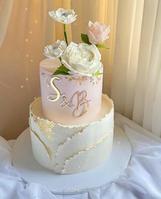 a three tiered cake with white flowers on top and the number two on it