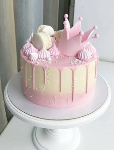 a pink and white cake with icing on it sitting on top of a table