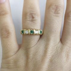 This stunning 18K yellow gold ring features two very white round brilliant cut diamonds and three bright green round emeralds. This ring is perfect for an anniversary band, wedding band, or stackable ring. The contrast of the colors makes sure this ring stands out! Metal: 18K Yellow Gold Diamonds: .20 CTW, VS1-VS2, E-F Color Emeralds: 3 MM Each Band Width: 3.44 - 5.00 MM Size: 7 For a greater selection of jewelry please visit our website at www.BlackMarketLLC.com If you have any questions about Green Emerald Ring With Single Cut Diamonds For Promise, Emerald Green Promise Ring With Single Cut Diamonds, Anniversary May Birthstone Emerald Ring With Single Cut Diamonds, Classic Green Rings With Single Cut Diamonds, Green Diamond Promise Ring With Single Cut Diamonds, Green Emerald Wedding Ring With Single Cut Diamonds, Heirloom Green Diamond Ring With Single Cut Diamonds, Classic Green Diamond Ring With Single Cut Diamonds, Classic Green Emerald Ring With Single Cut Diamonds