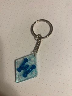 a blue teddy bear keychain is on a white table with polka dot paper