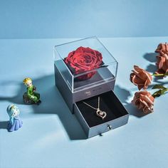 an open jewelry box with a rose in it next to other small figurines