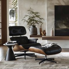 an eames chair and ottoman in front of a large window with a painting on the wall