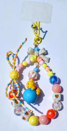 a bunch of colorful beads and charms on a white surface with a name tag attached to it