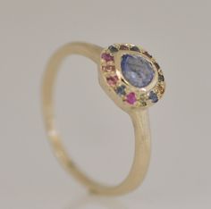 Unique gold ring with Sapphire gemstones and Tanzanite. 18k solid gold ring with light purple Tanzanite central stone and 13 multicolor Sapphire stones. There are Blue Sapphires, Pink Sapphires, green and yellow Sapphires. The ring is 18k solid yellow gold in a scratched natural finish, a gorgeous ring for a woman. This is a perfect statement handmade ring that you would not see. A perfect gift for someone you love or for yourself! The central stone has a unique purple color and a not ordinary s Yellow Gold Sapphire Rings With Multi-stone, Yellow Gold Multi-stone Sapphire Ring, Multicolor Halo Ring As Gift, Multicolor Halo Rings As A Gift, Multicolor Halo Rings For Gift, Multicolor Multi-stone Cluster Ring As Gift, Yellow Gold Tanzanite Multi-stone Ring, Multi-stone Sapphire Ring In Yellow Gold, Yellow Gold Gemstones With Halo Setting For Gift