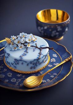 a blue and gold plate with a cake on it next to a golden bowl filled with flowers