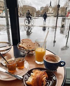 a table topped with plates of food and cups of coffee next to each other on top of a wooden table