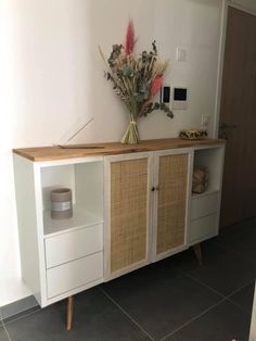 a vase with flowers on top of a white cabinet