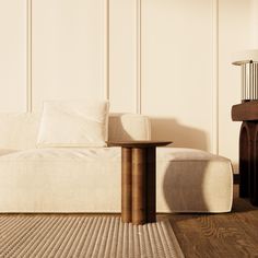 a white couch sitting next to a wooden table on top of a hard wood floor