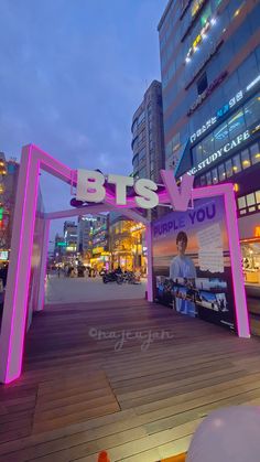 a sign that says bts and people you on it in front of some buildings