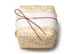 a basket wrapped in white paper and tied with a red ribbon, on a white background