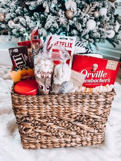 a basket filled with snacks next to a christmas tree