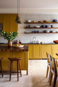 a kitchen with yellow cabinets and wooden stools