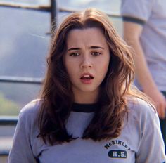 a woman with long brown hair wearing a grey shirt