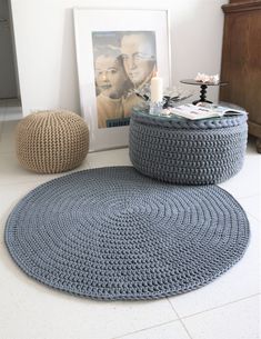 two crocheted round ottomans on the floor next to a coffee table with a candle