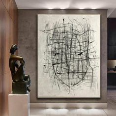 an abstract painting hangs on the wall next to a statue