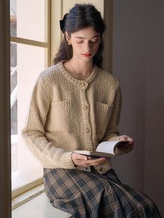 a woman sitting on a window sill reading a book