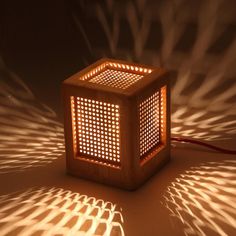 a wooden lamp that is turned on with the light reflecting off it's sides