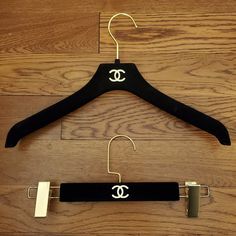 two black hangers are hanging on a wooden wall and one has a metal bar attached to it