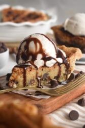 a piece of cake with ice cream and chocolate sauce on top sitting on a plate